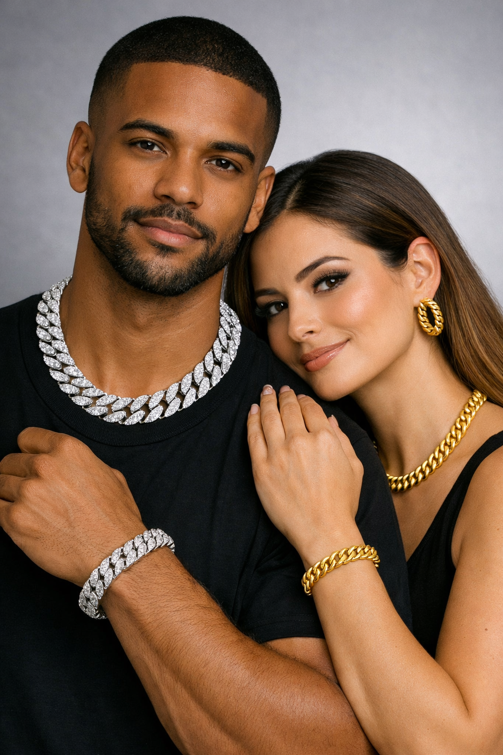 Diverse couple wearing white‑gold and yellow‑gold Cuban link jewelry on neutral background.