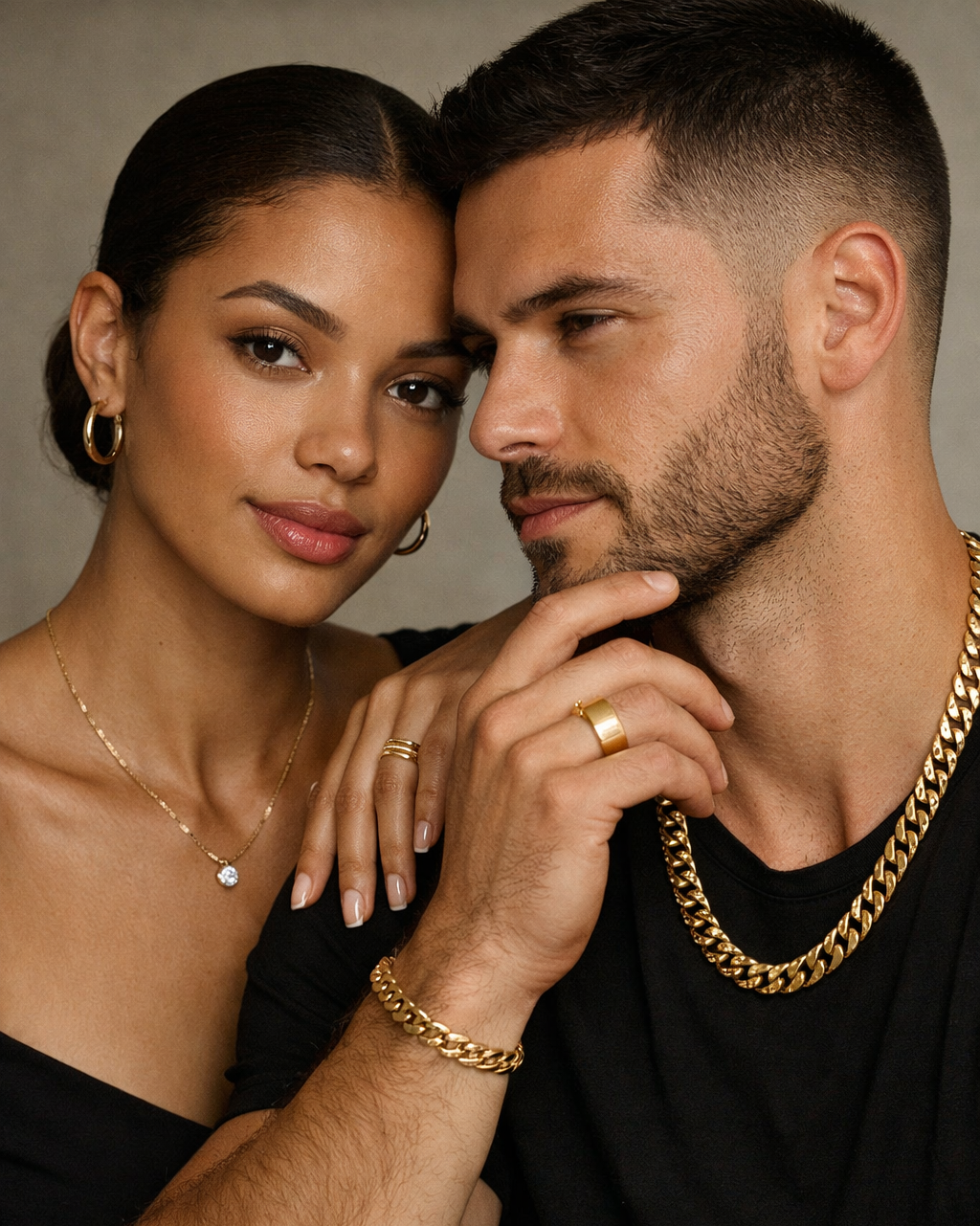 Male and female models wearing solid 14k gold jewelry — hoop earrings, diamond pendant necklace, Cuban link chain, and gold rings — editorial close‑up.