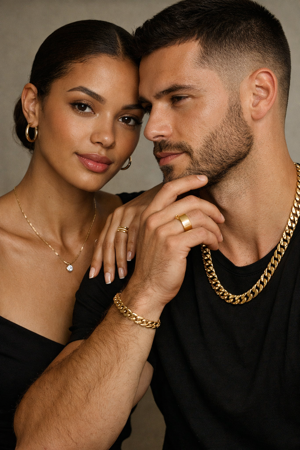 Male and female models wearing solid 14k gold jewelry — hoop earrings, diamond pendant necklace, Cuban link chain, and gold rings — editorial close‑up.