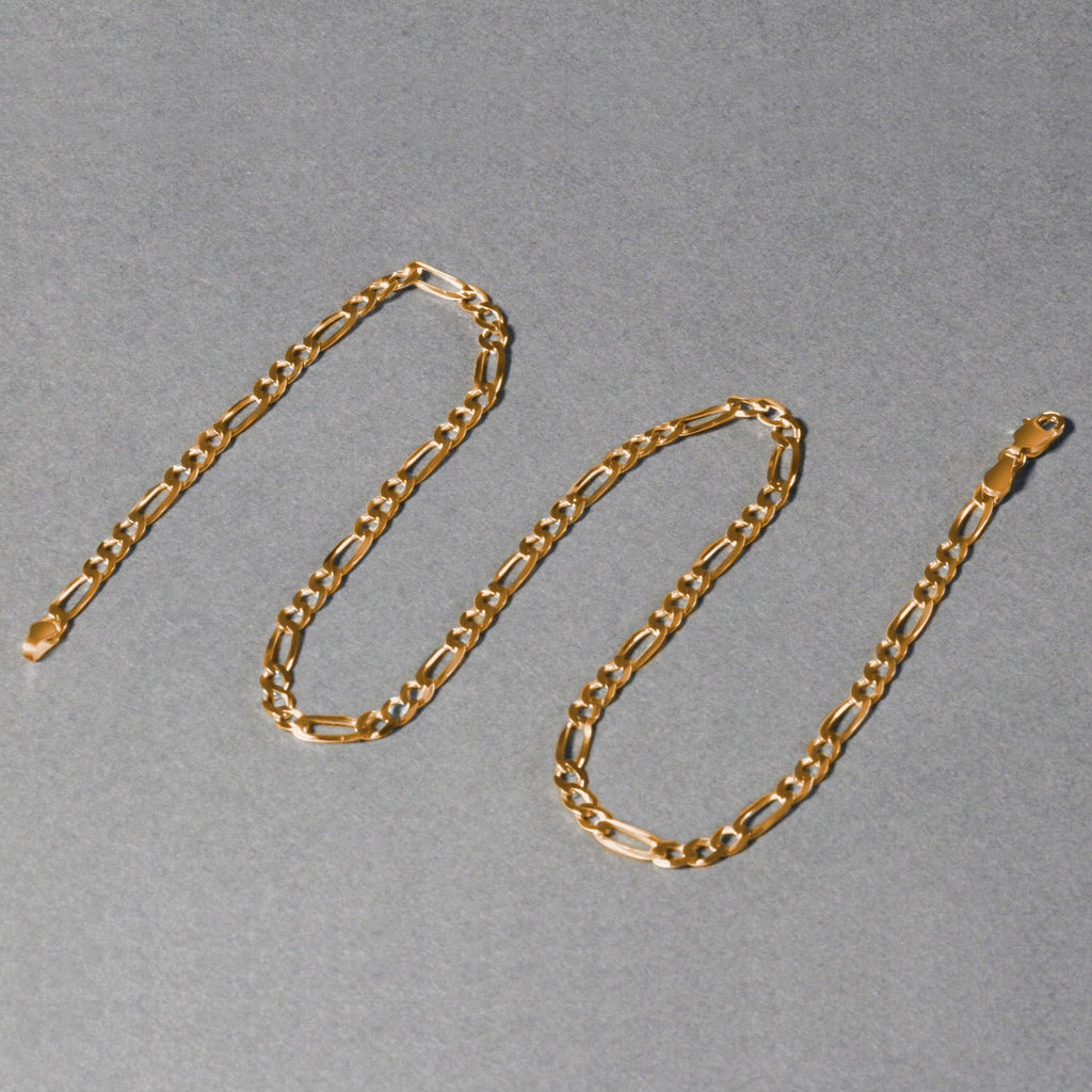 14K yellow gold solid Figaro chain, 3.80mm, arranged in an S‑shape on a white background to highlight polished long‑and‑short links and solid gold craftsmanship.