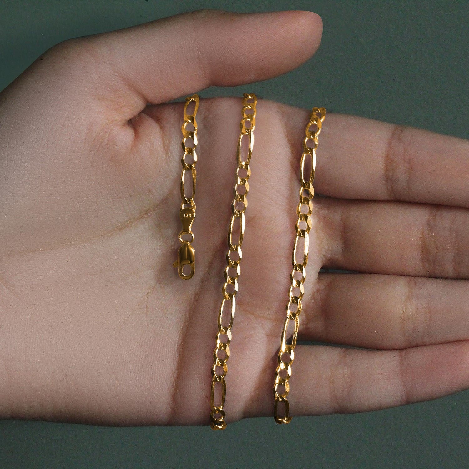 14K yellow gold solid Figaro chain, 3.80mm, wrapped around the palm of a hand to show real‑life scale, polished long‑and‑short links, and solid gold craftsmanship.